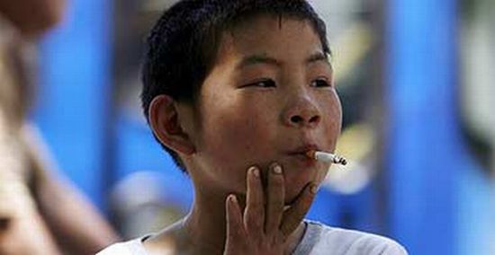a seven year old chinese boy smokes a cigarette in